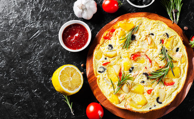 omelette with salmon fish, vegetables and olive in a plate on dark background