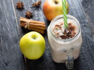 Apple smoothie or cinnamon milkshake on a dark wooden table
