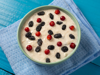 Oatmeal with cranberries and raisins on a wooden blue table
