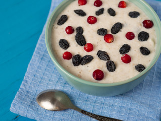 Oatmeal with cranberries and raisins on a wooden blue table