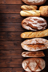 Assortment of baked bread and bread rolls on wooden table background