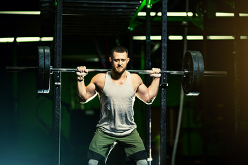 Fototapeta na wymiar Man with heavyweight barbell in the dark gym.