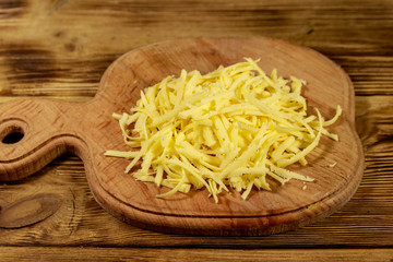 Grated cheese on cutting board on wooden table