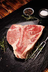 Raw T-bone steak on stone cutting board.