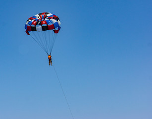 parasail with two swimmers hanging above the ocean while being pulled by motor boat