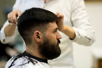 Obraz premium Bearded Man with black hair, having a haircut at a Chinese barbershop