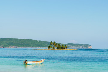 Fototapeta na wymiar Landscape od turquoise sea and small tropical island with palm trees and fisherman boat in Las Galeras- Dominican Republic. 