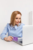 Office woman holding purple credit card and making shopping online at her workplace