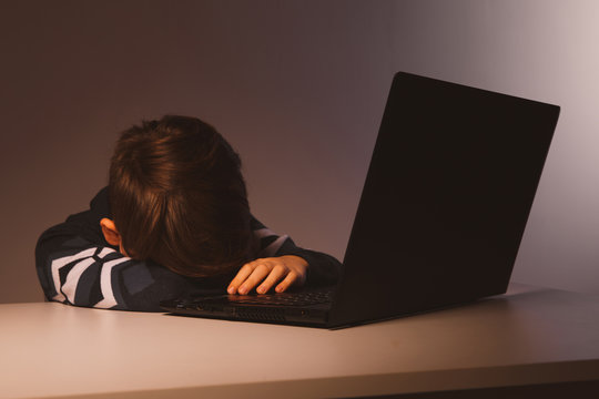 Closeup picture of bullying teen boy feeling upset infront of computer. Stressed sad boy is bullying by his classmates