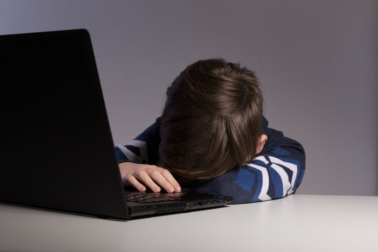 Closeup picture of bullying teen boy feeling upset infront of computer. Stressed sad boy is bullying by his classmates