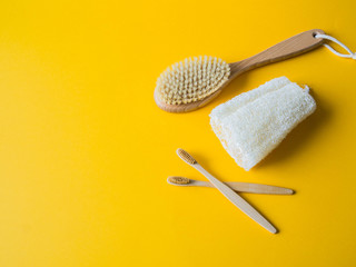 Wooden body Brush with handle, loofah wisp of bast, bamboo toothbrushes on a yellow background.