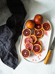 Raw blood red orange slice on oval plate a gray background. Citrus background, top view