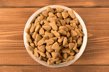 Bowl with dog food on a wooden table. Close up.