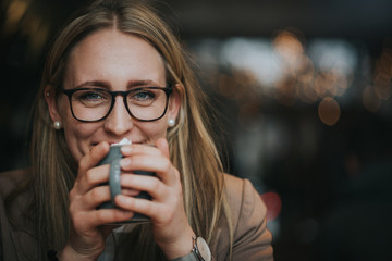 hübsche junge, lachende Frau trinkt kaffee, kakao mit Sahne in einem Cafe