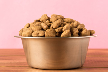 Bowl with dog food on a wooden table. Close up.