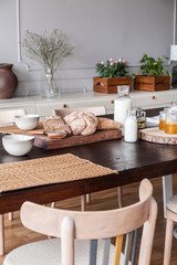 Milk, natural honey and homemade bread on cottage wooden table in dining room interior of stylish rustic apartment, real photo