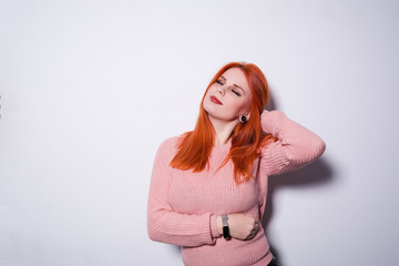 Fototapeta premium Red-haired girl is embarrassed. Portrait of woman at swallow wall