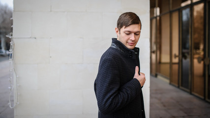 lateral view of a young man in a classic coat outdoors