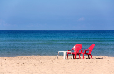 Fototapeta na wymiar morning beach with red armchairs on blue sea background