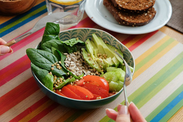 Woman is eating healthy lunch on colorful background. Buddha bowl. Healthy food concept