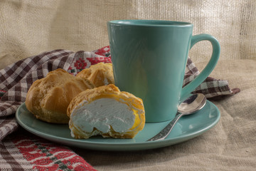 Delicious eclairs with custard, a beautiful green mug with a drink