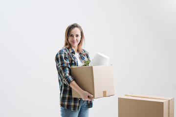 Young beautiful girl with colored hair in a white T-shirt, plaid shirt and jeans, against the background of cardboard boxes and things.