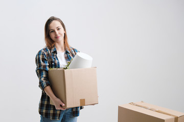 Young beautiful girl with colored hair in a white T-shirt, plaid shirt and jeans, against the background of cardboard boxes and things.