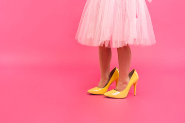 Little girl in oversized shoes with space for text, closeup on legs isolated on pink.