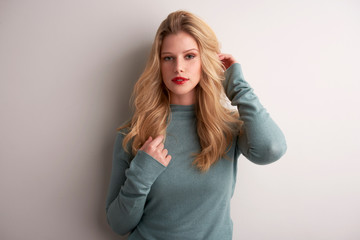 Studio portrait of beautiful young woman standing at grey background