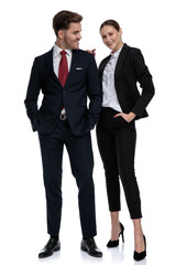 couple in business suits standing together with hands in pockets