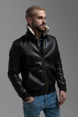 blonde guy in blue jeans and leather jacket looking away
