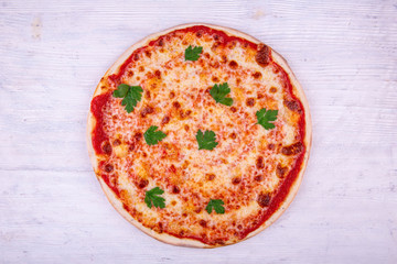 Pizza Margarita with parsley on a white wooden background