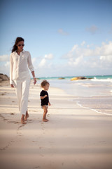 Fototapeta na wymiar Mother and beby girl walking on tropical beach