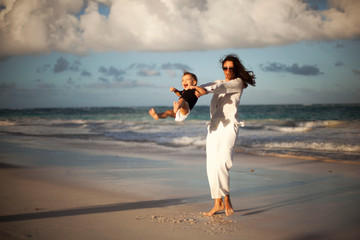 Mother and daughter having fun on tropical beach - Mum playing with her kid in holiday vacation next to the ocean - Family lifestyle and love concept