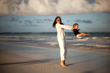 Mother and daughter having fun on tropical beach - Mum playing with her kid in holiday vacation next to the ocean - Family lifestyle and love concept