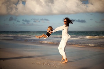 Mother and daughter having fun on tropical beach - Mum playing with her kid in holiday vacation next to the ocean - Family lifestyle and love concept