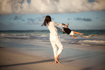 Mother and daughter having fun on tropical beach - Mum playing with her kid in holiday vacation next to the ocean - Family lifestyle and love concept