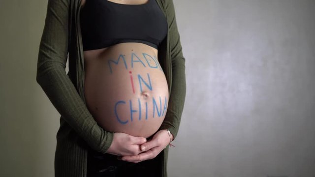 Pregnant woman rotates with an inscription made in China on her belly. 4K.