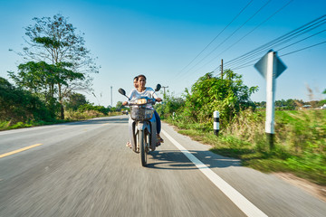thai mother and daughter riding motorbike through rural thailand