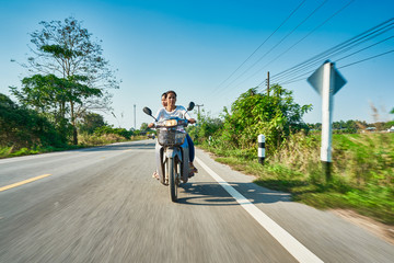 Obraz premium thai mother and daughter riding motorbike through rural thailand