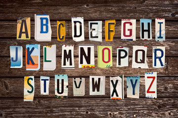 Alphabet set created with broken pieces of vintage car license plates on wooden planks background
