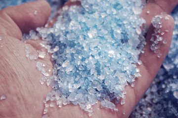 hand with sea salt on sea salt background