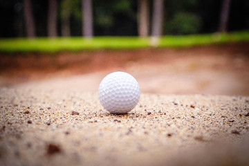 Golf ball on sand bunker in beautiful golf course at sunset background. Golf ball on green in golf course at Thailand