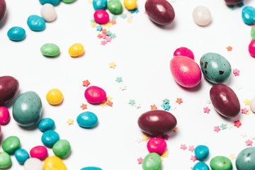Easter colorful eggs and big chocolate egg flat lay on white background. Top view, copyspace for text.