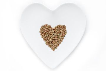 Lentils lie in the shape of a heart on a white plate