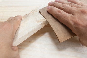 Worker Man Polishing Sandpaper Wood by hand.