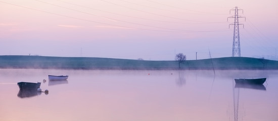 Pylon pollution in countryside landscape telephone cable line at sunset at boat lake