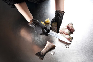 Usuwanie łusek z ryby. Kucharz  oprawia pstrągi © foodandcook
