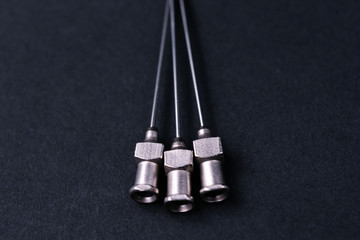 Old rare metallic medical needles isolated on gray background. Needles new and clean. Top view. Sharp needle tips not visible on photo.