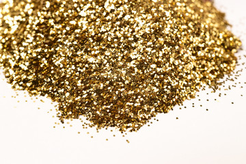 A bunch of golden nail gritter for manicure. Golden glitter shining on daylight. Stock photo isolated on white background. Nail varnish topping.
